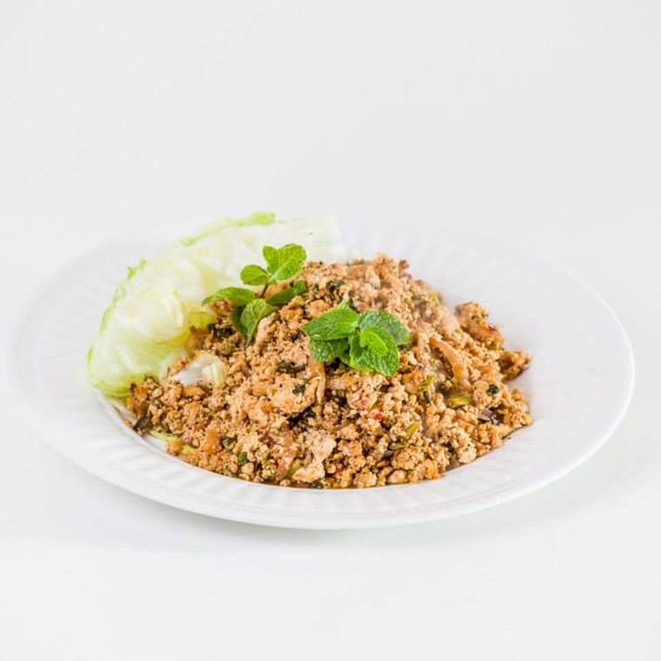 Thai Larb Gai, a minced chicken salad with mint and lettuce, on a white plate.